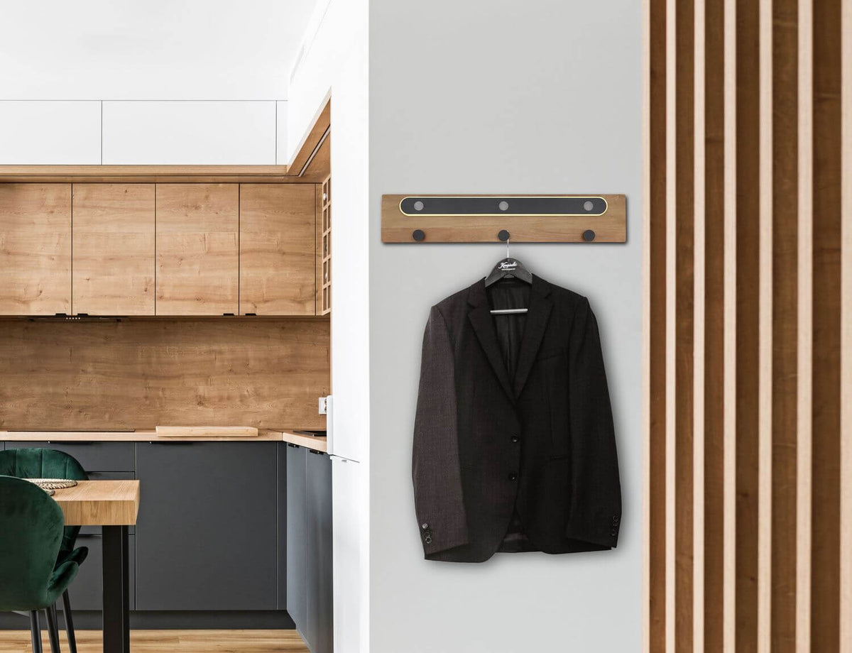 Mise en ambiance sur un mur, manteau noir suspendu près d'une cuisine.