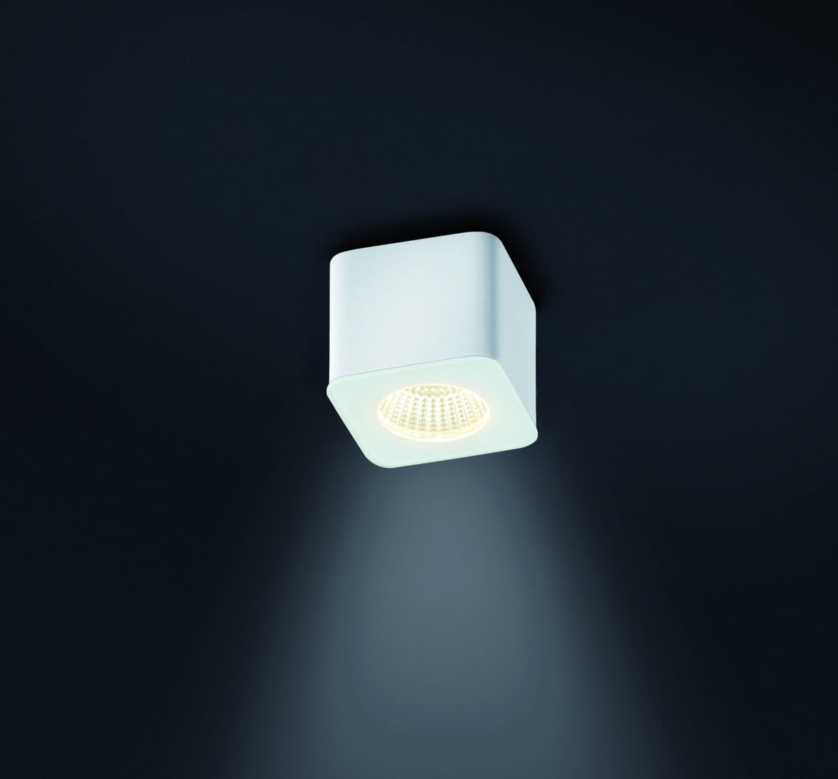 Vue de face d'un plafonnier extérieur blanc carré avec diffuseur LED allumé.