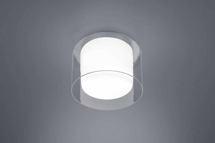 Gros plan du luminaire rond allumé avec diffuseur blanc et contour transparent.