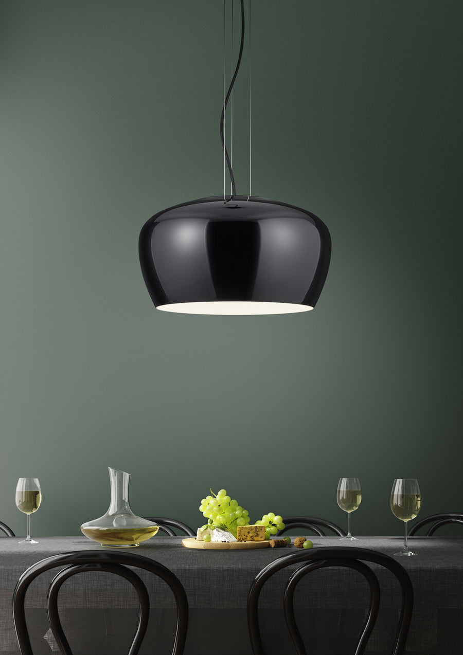 Suspension noire brillante éclairée au-dessus d'une table dressée, intérieur blanc.