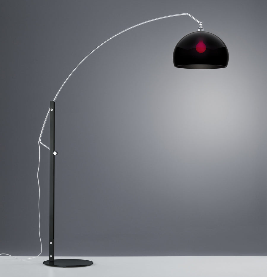 Lampadaire noir de profil sur fond gris, bras chromé arqué et dôme