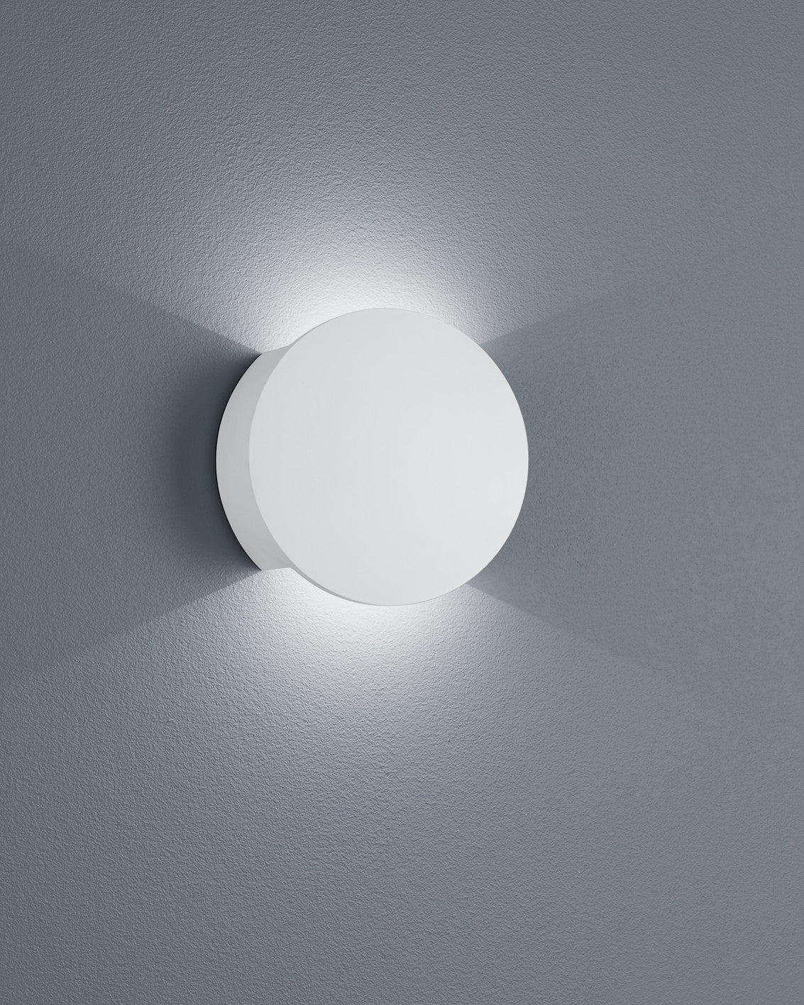 Applique ronde blanche en plâtre, vue de face sur mur gris texturé