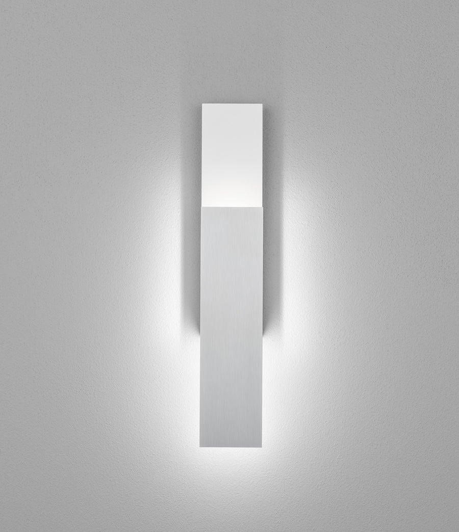 Détail de la barre verticale blanche éclairée par le bas sur fond de mur texturé