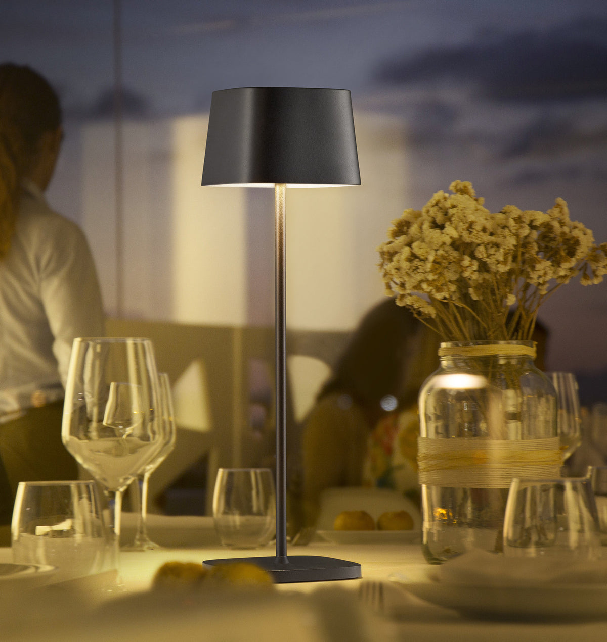 Mise en ambiance nocturne sur table de restaurant, verres et bouquet séché