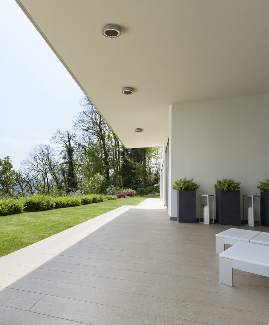 Terrasse couverte contemporaine équipée de trois plafonniers ronds anthracite alignés au plafond