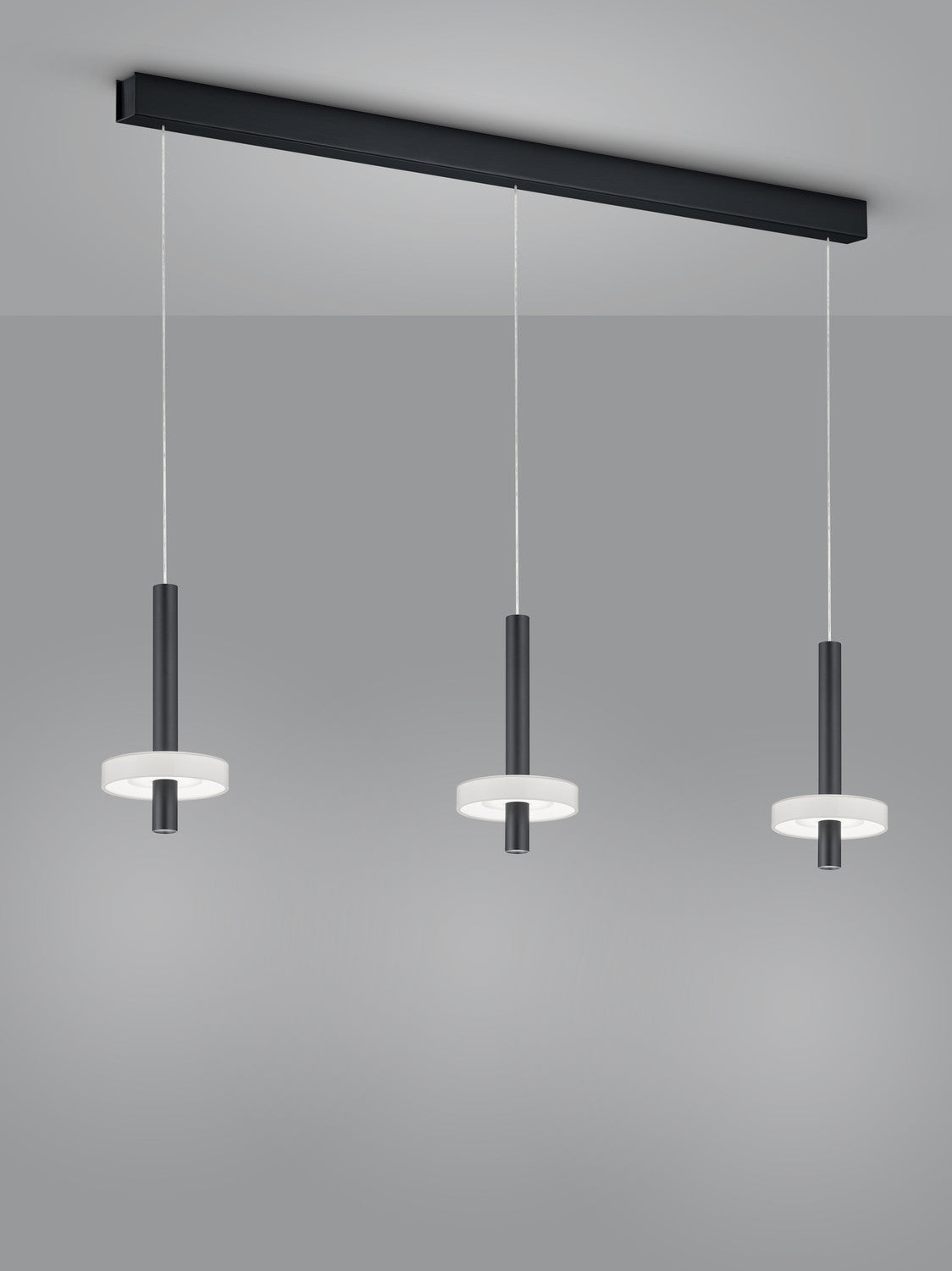 Détail rapproché des trois cylindres noirs et de leurs anneaux lumineux blancs.