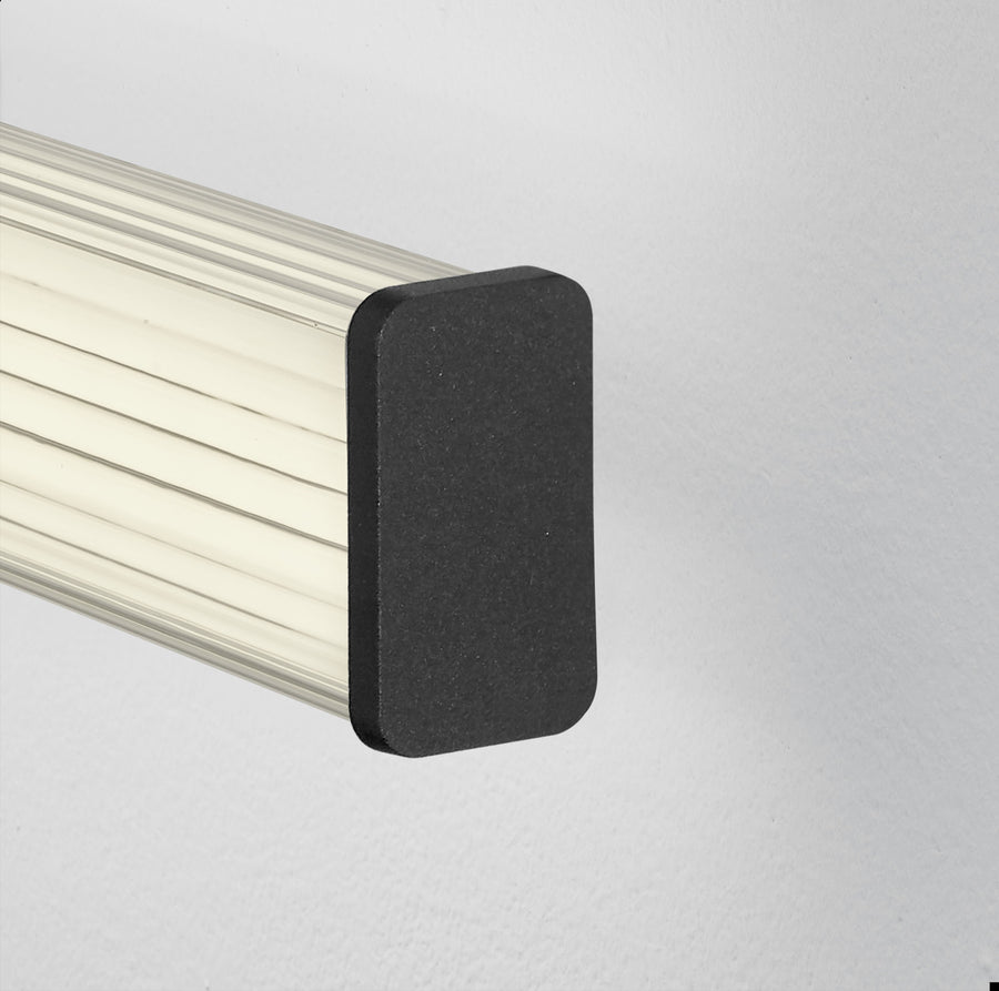 Gros plan sur l'embout noir mat et le diffuseur strié blanc de l'applique