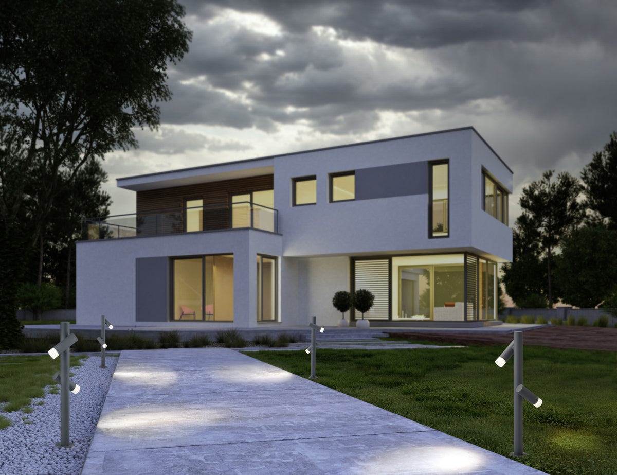 Mise en ambiance nocturne, bornes anthracite éclairant une allée devant une maison moderne