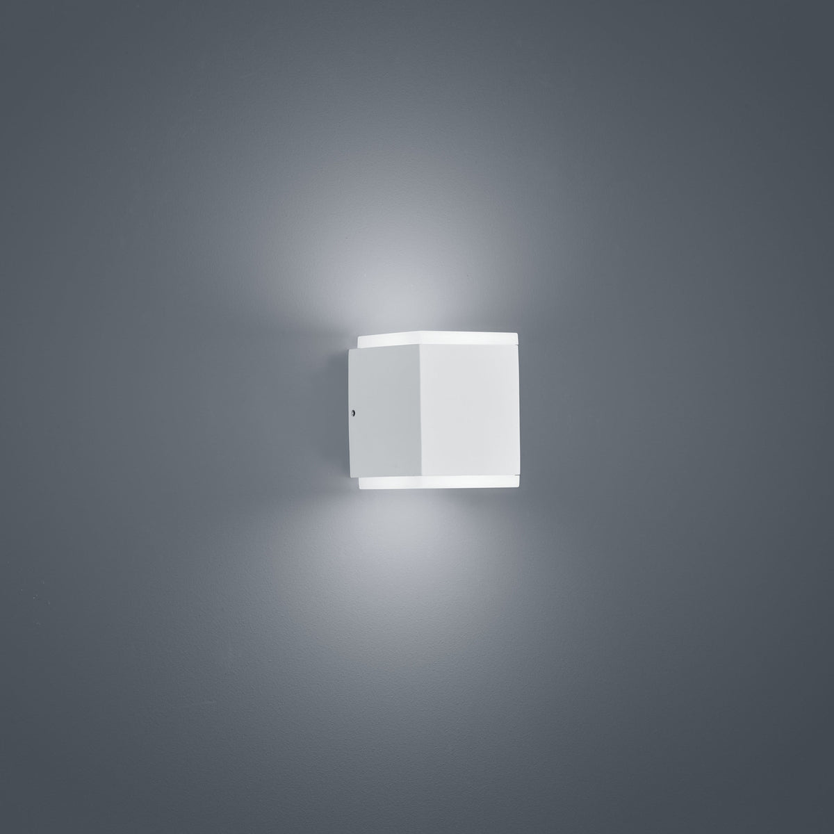 Vue de trois quarts du luminaire blanc, montrant la platine de fixation murale et sa forme carrée.