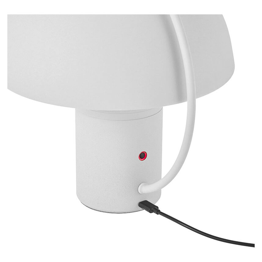 Détail du pied cylindrique blanc avec interrupteur rouge et câble d'alimentation noir.