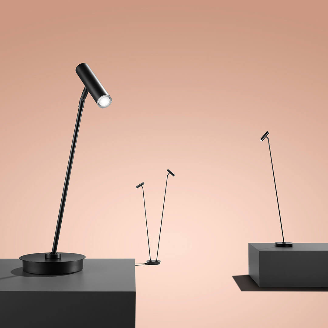 Mise en ambiance sur fond pêche, trois lampadaires noirs exposés sur des socles minimalistes