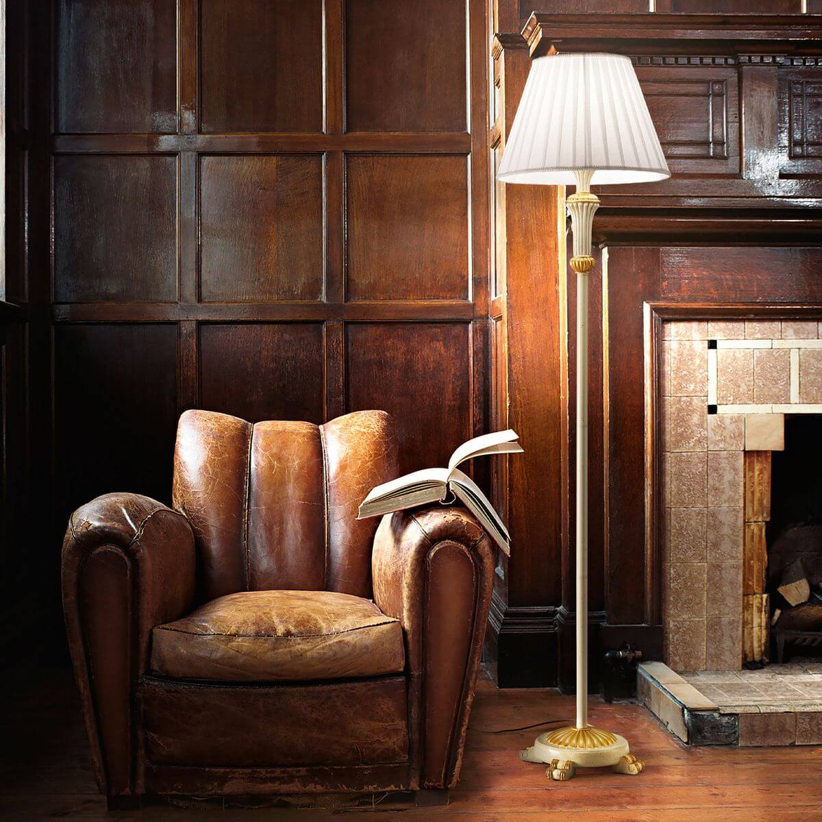 Lampadaire allumé dans un salon en bois avec fauteuil en cuir et cheminée.