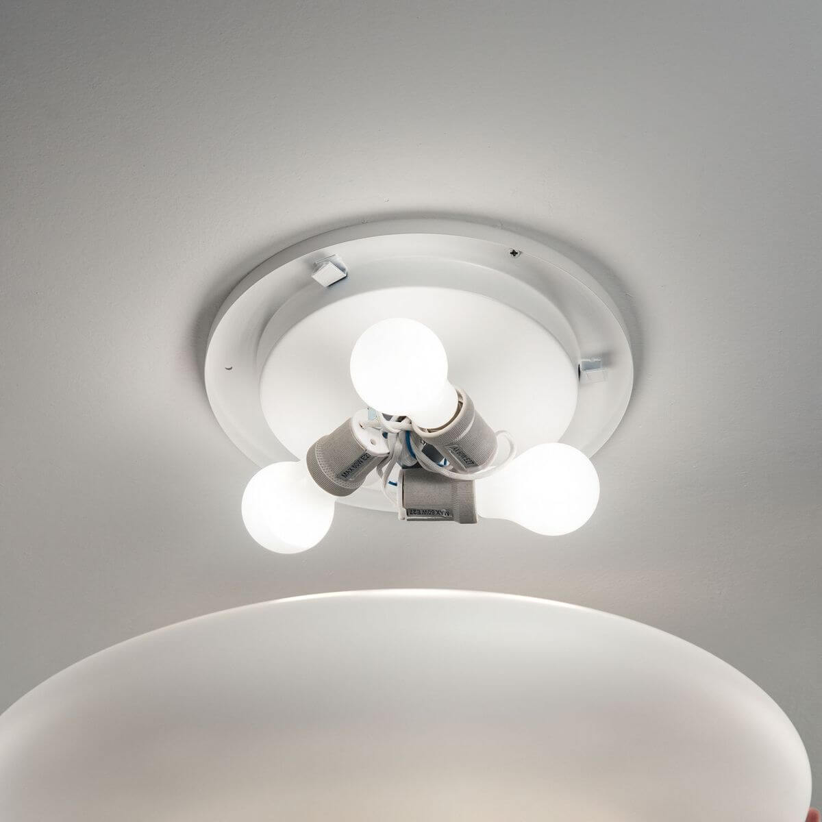 Détail du montage intérieur montrant les douilles et les ampoules allumées sous le diffuseur