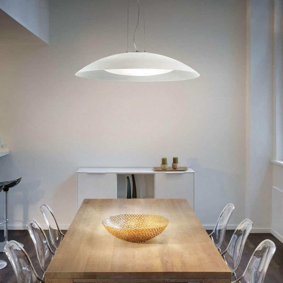 Salle à manger moderne avec suspension blanche au-dessus d'une table en bois et chaises transparentes