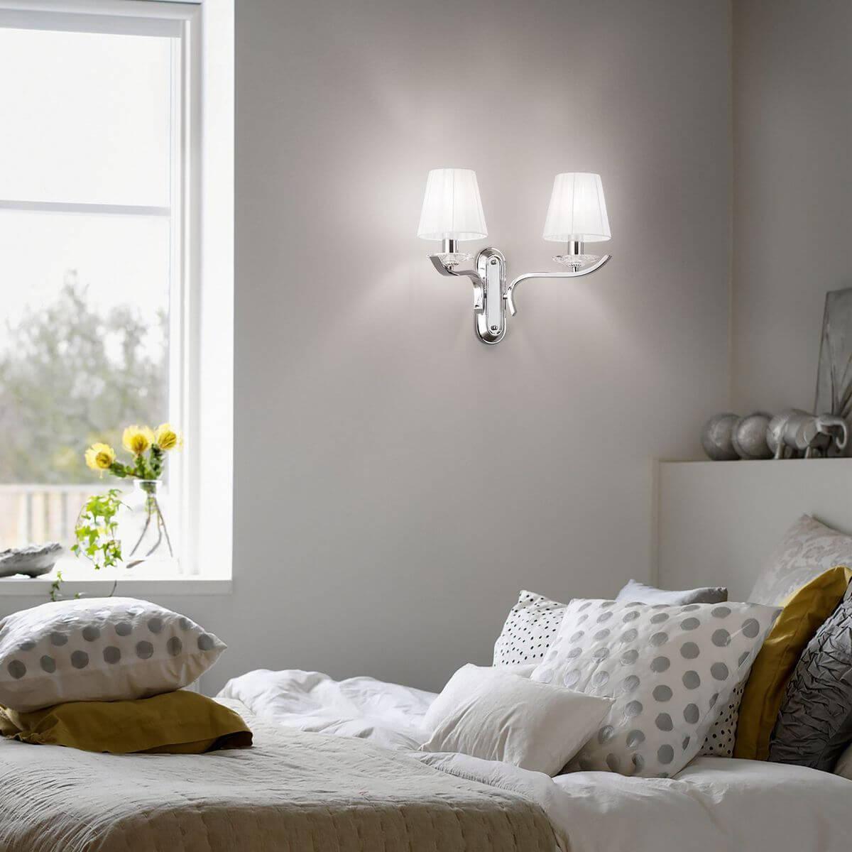 Applique murale allumée dans une chambre, fixée au mur au-dessus d'un lit garni de coussins