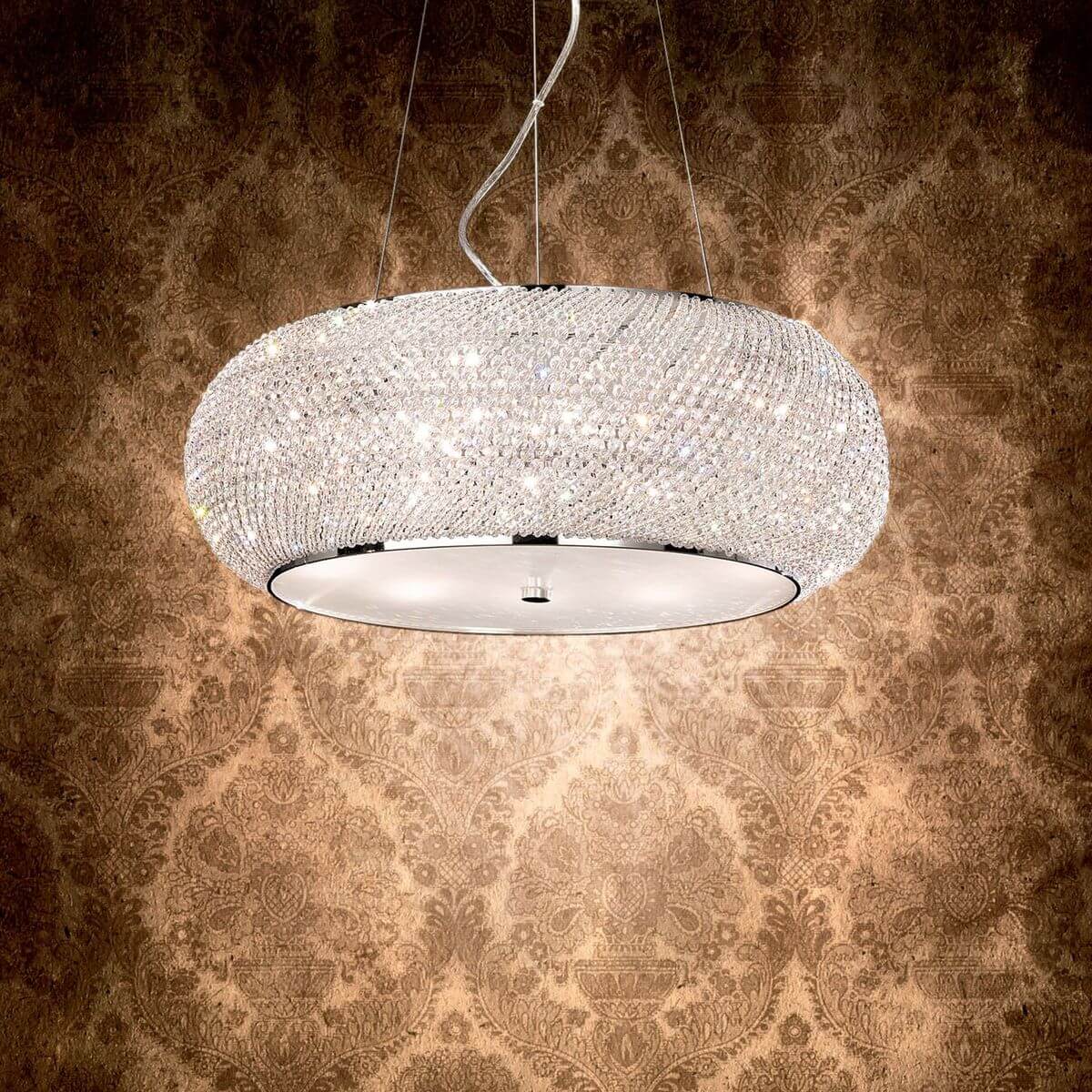 Luminaire allumé devant un papier peint damassé, halo lumineux diffus sur le mur