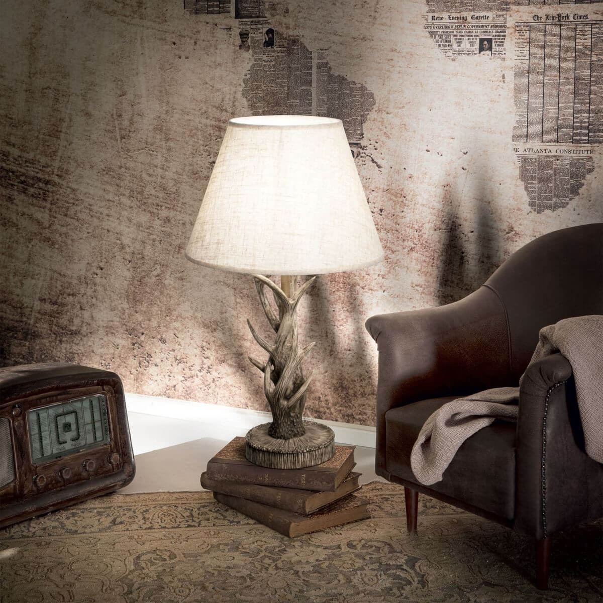 Mise en ambiance vintage avec lampe posée sur des livres, fauteuil en cuir et radio ancienne