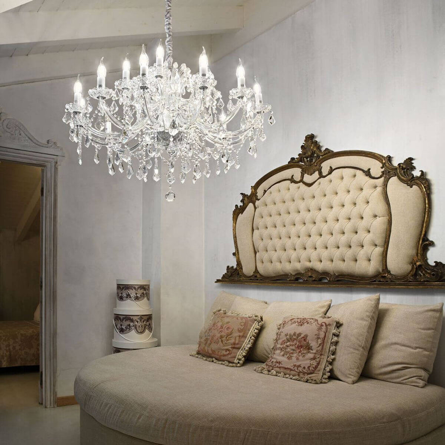 Suspension en cristal allumée dans une chambre, au-dessus d'un lit capitonné de style ancien.