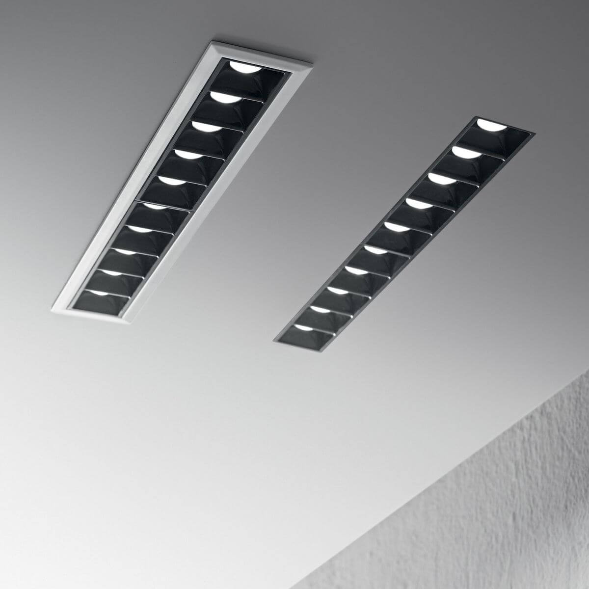 Deux luminaires linéaires encastrés dans un plafond blanc, mise en ambiance