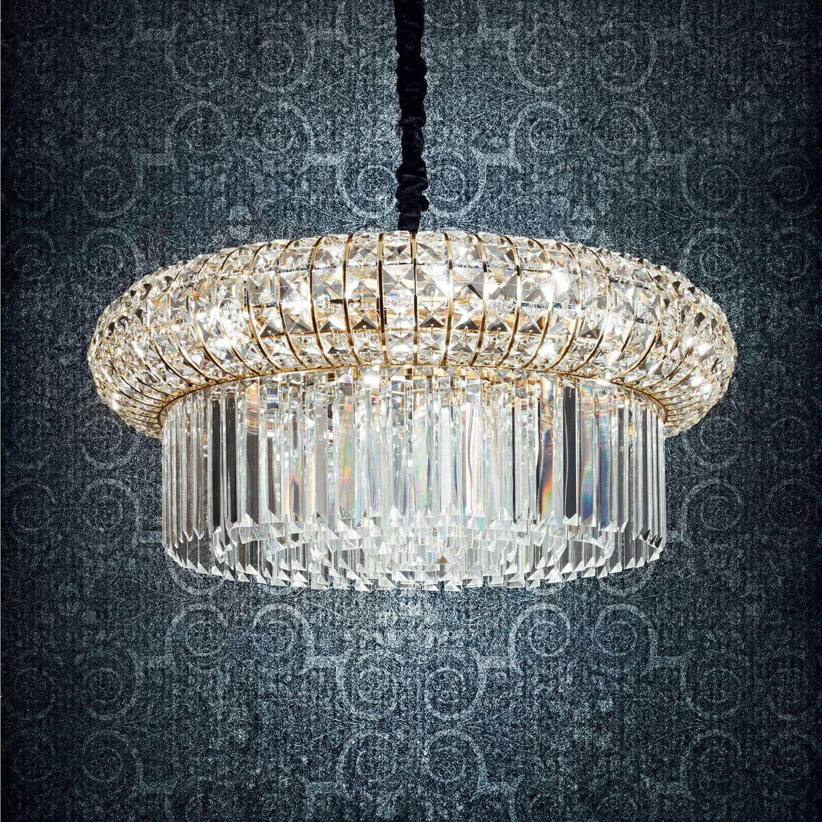 Gros plan du luminaire illuminé devant papier peint à motifs, reflets irisés des facettes