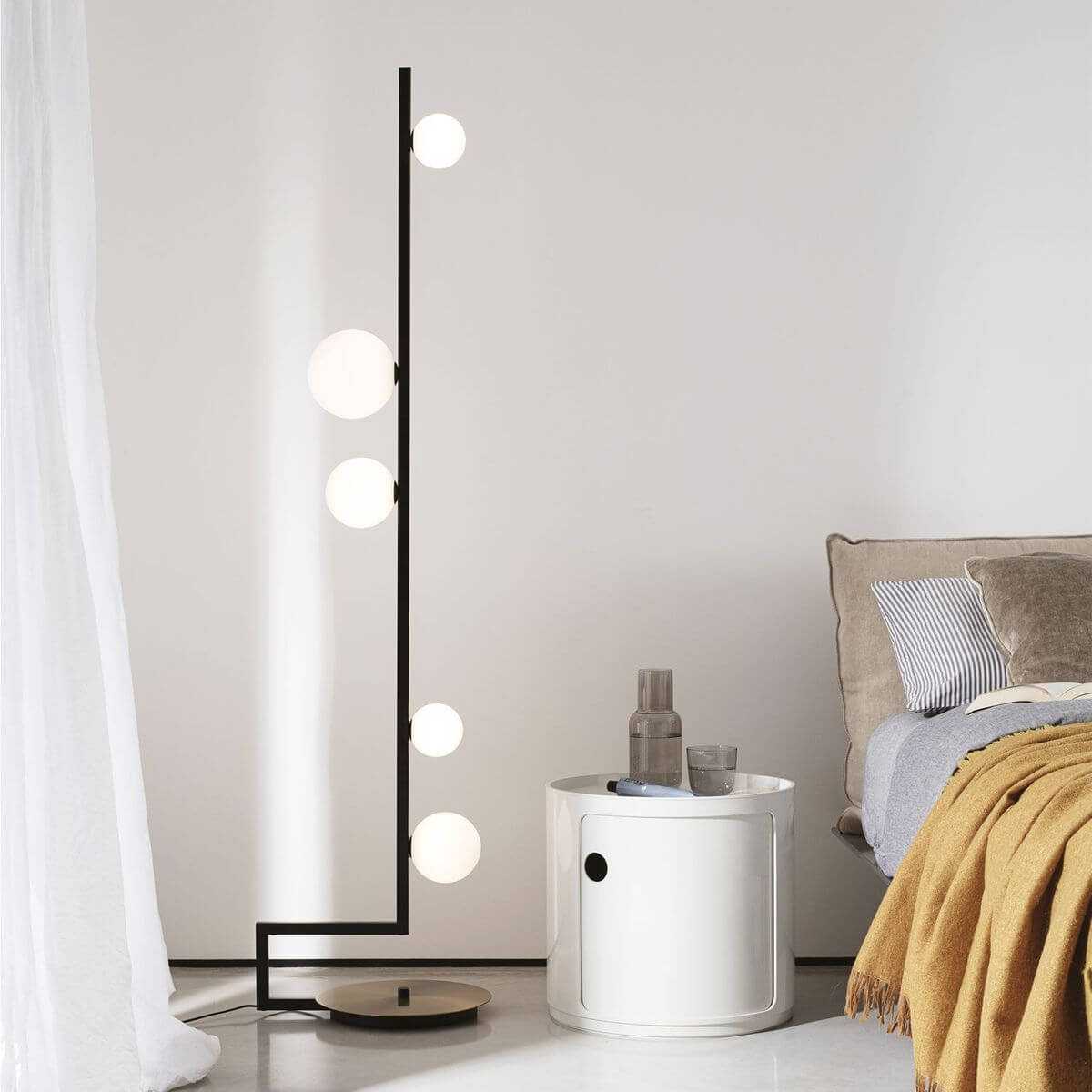 Mise en ambiance d'une chambre avec lampadaire allumé près du lit et table de chevet.