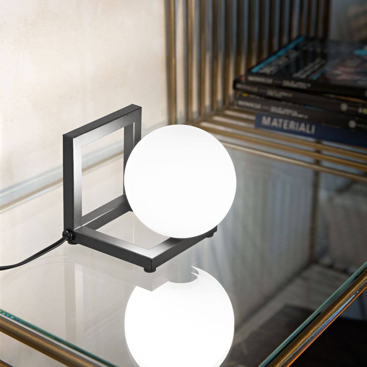 Lampe allumée posée sur une table en verre, reflet de la sphère blanche