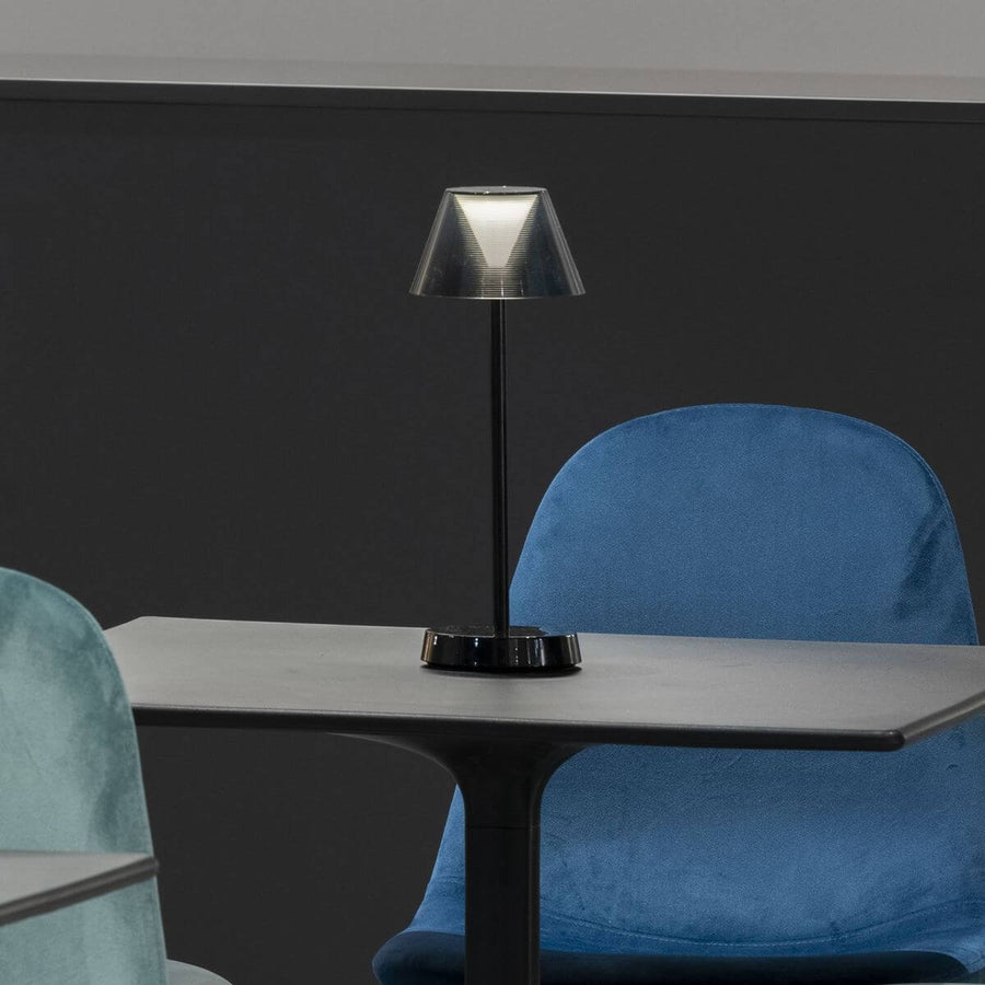 Lampe allumée posée sur une table devant des chaises bleues en intérieur