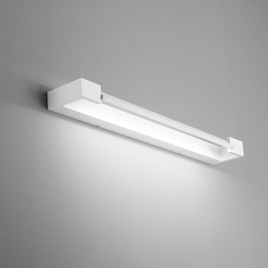 Applique murale blanche allumée diffusant une lumière rasante sur mur gris