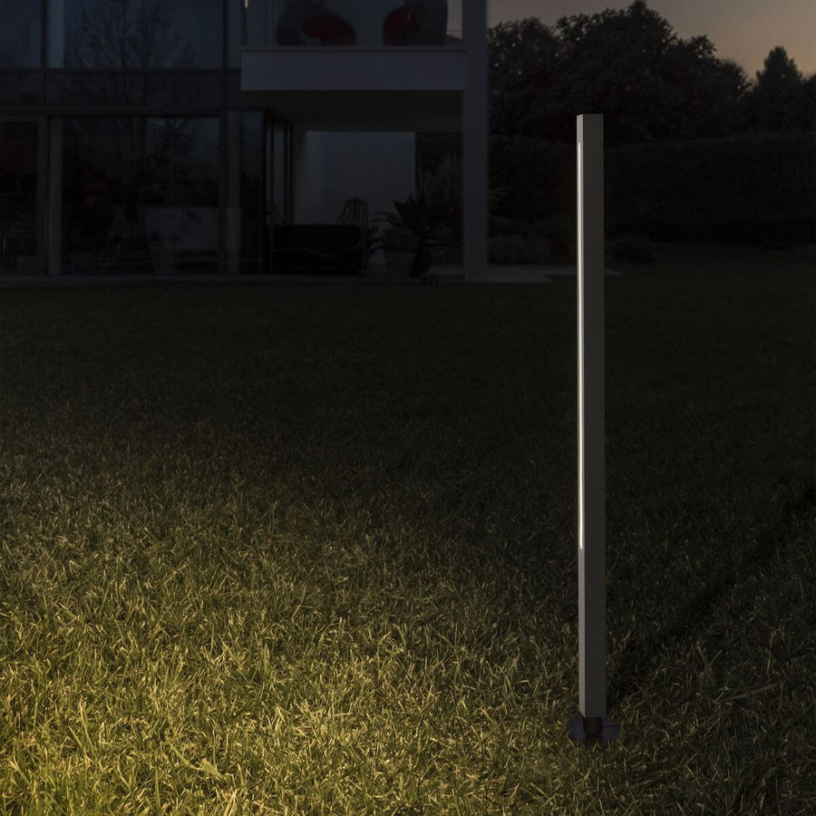 Lampadaire sur piquet éclairant une pelouse devant une maison moderne