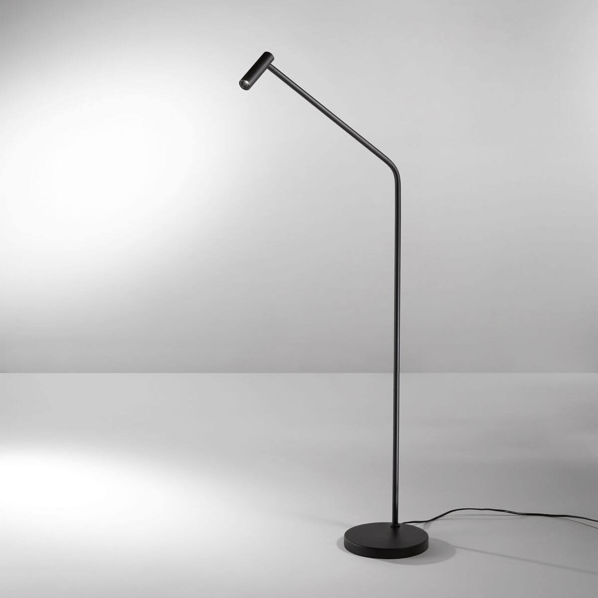 Mise en ambiance du lampadaire allumé éclairant un mur gris, câble au sol