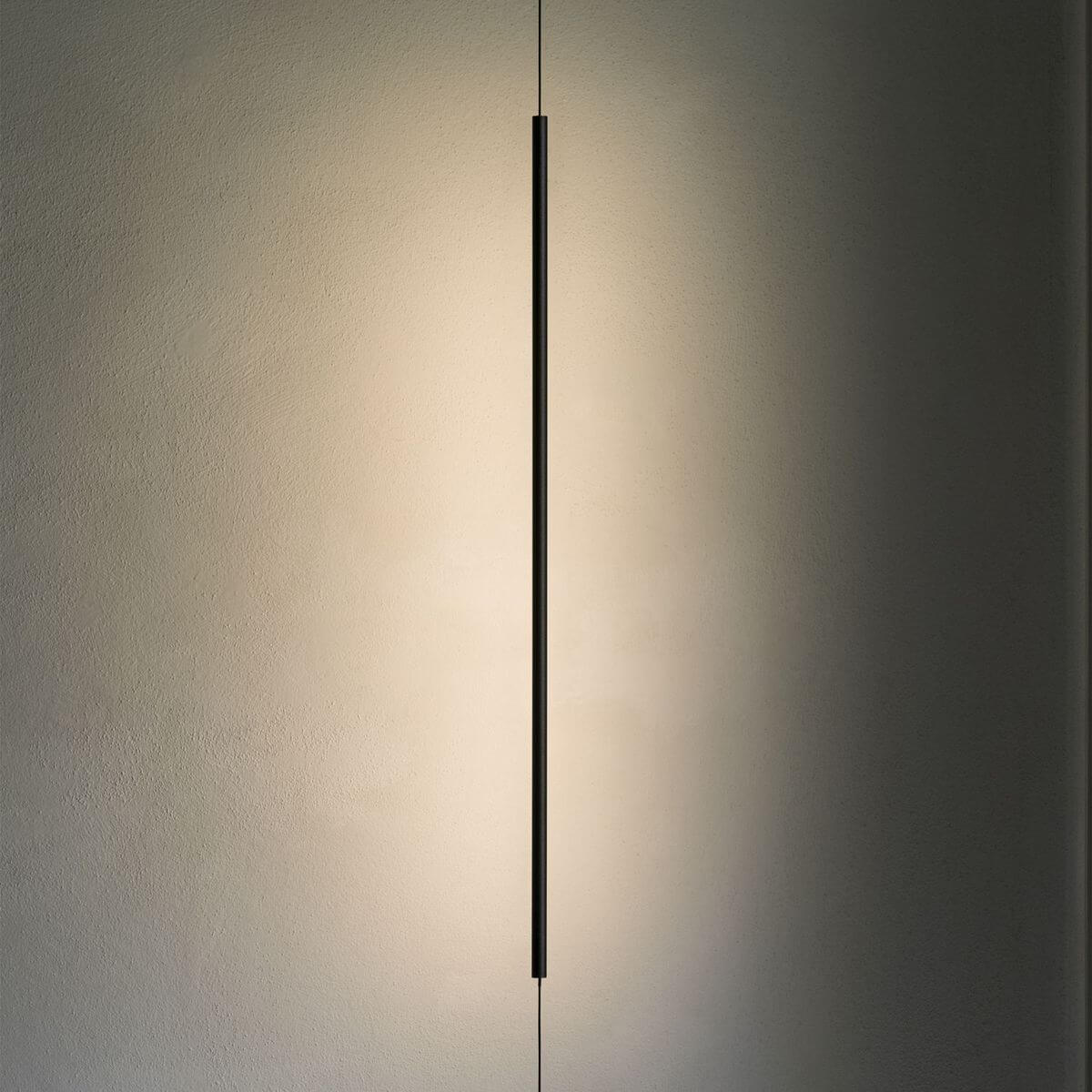 Le tube noir allumé projette un halo de lumière chaude sur un mur texturé