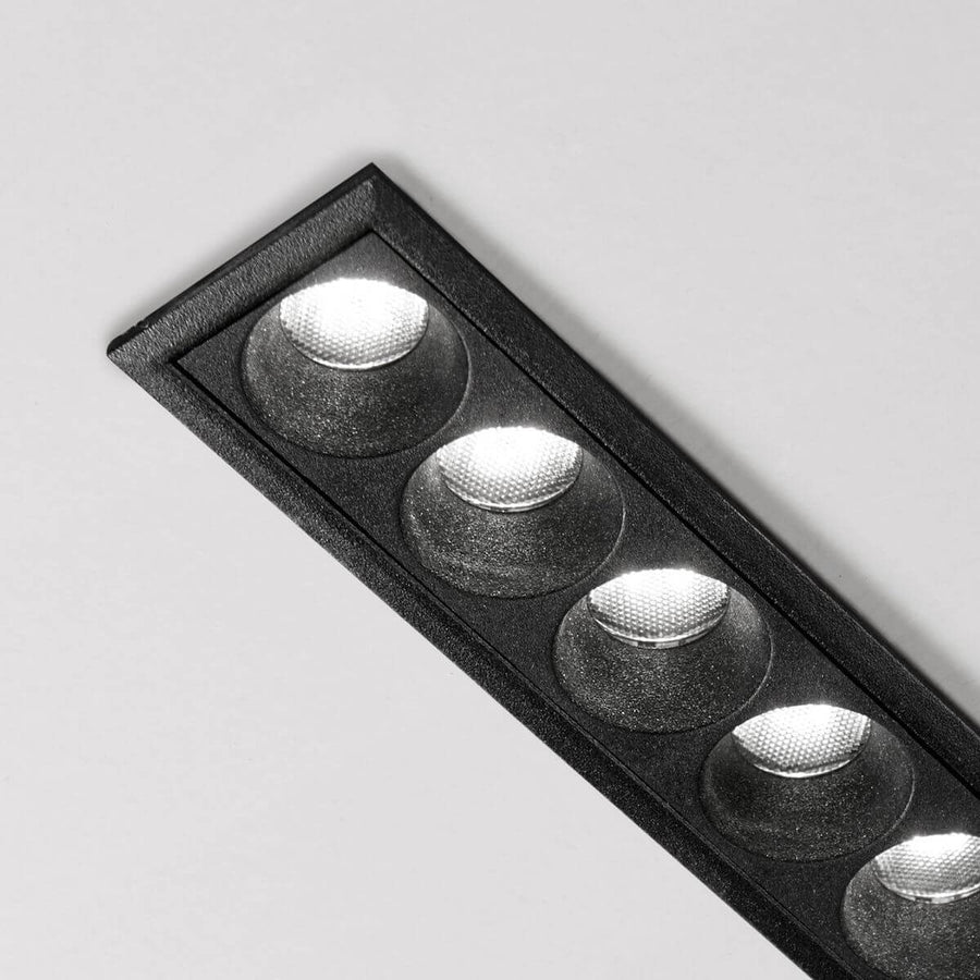 Détail rapproché de la finition noire granuleuse et des lentilles striées du spot