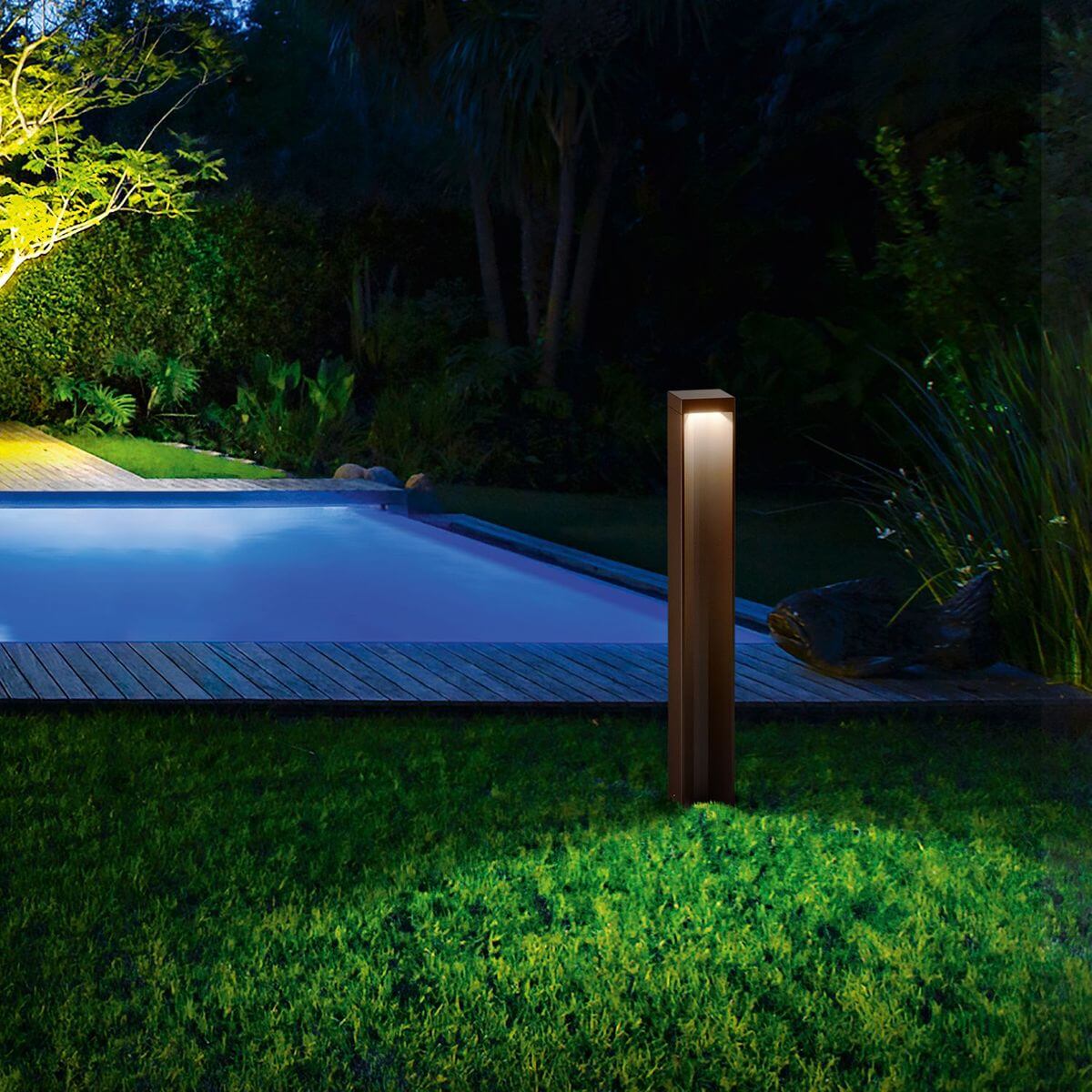 Mise en ambiance nocturne, luminaire éclairant une pelouse près d'une piscine.