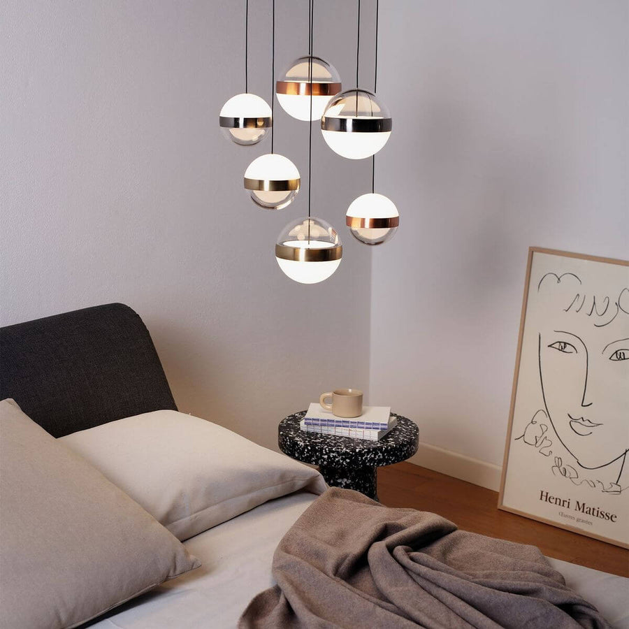 Suspension allumée au-dessus d'une table de chevet dans une chambre avec lit et affiche.