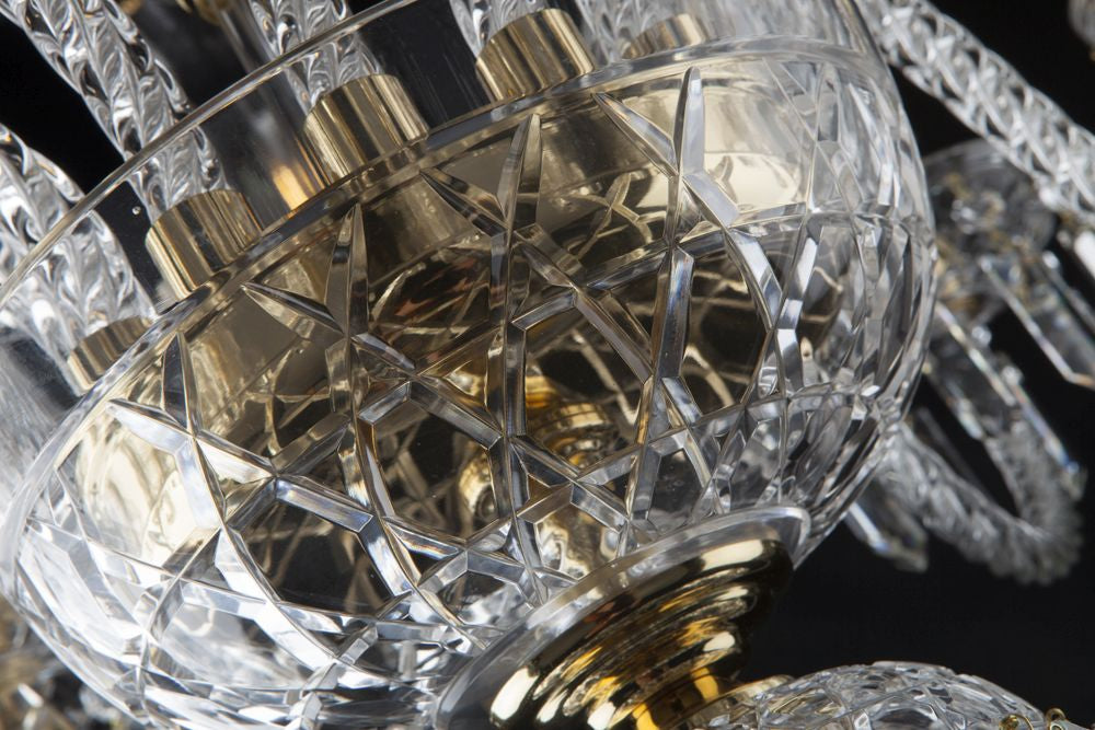 Gros plan sur la boule centrale en cristal taillé et les douilles dorées du luminaire.