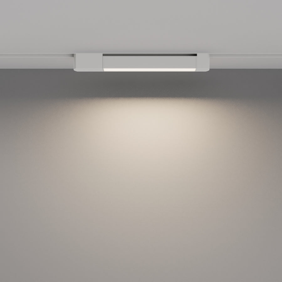 Luminaire allumé projetant un halo de lumière chaude sur le mur gris.