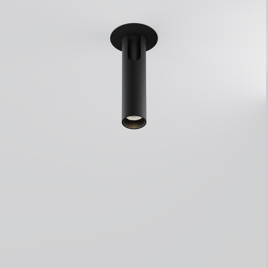 Spot cylindrique noir monté verticalement au plafond, éclairage dirigé vers le bas.