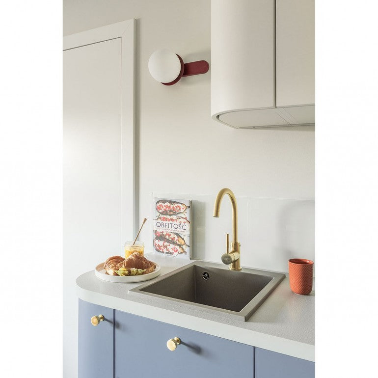 Ambiance cuisine, applique rouge au-dessus de l'évier et robinet doré.