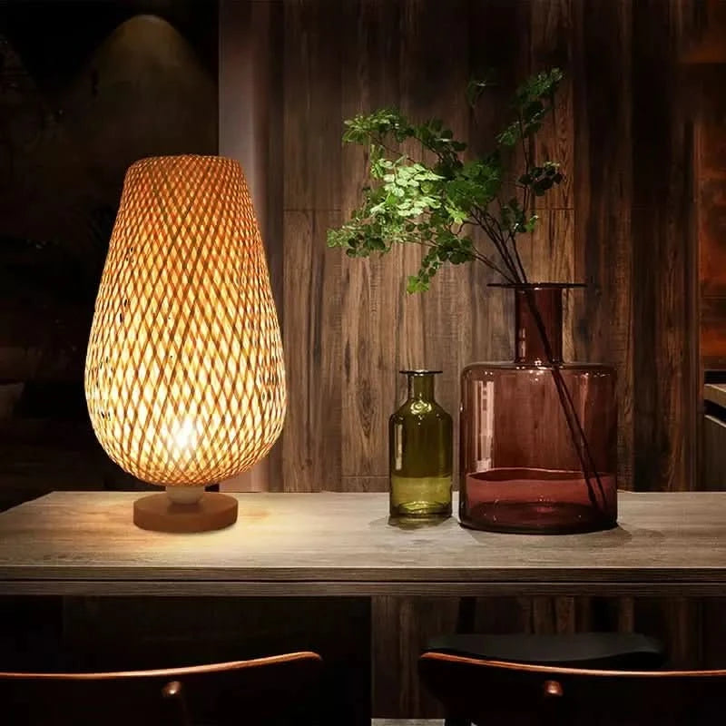 Détail de la lumière chaude traversant le tressage, vases colorés et branches sur table en bois