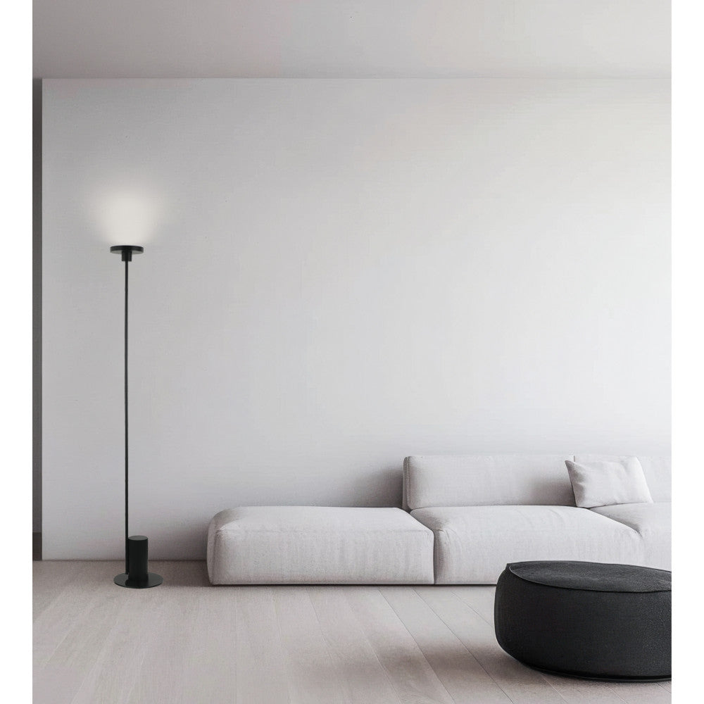 Lampe sur pied noire allumée devant un canapé blanc dans un salon minimaliste