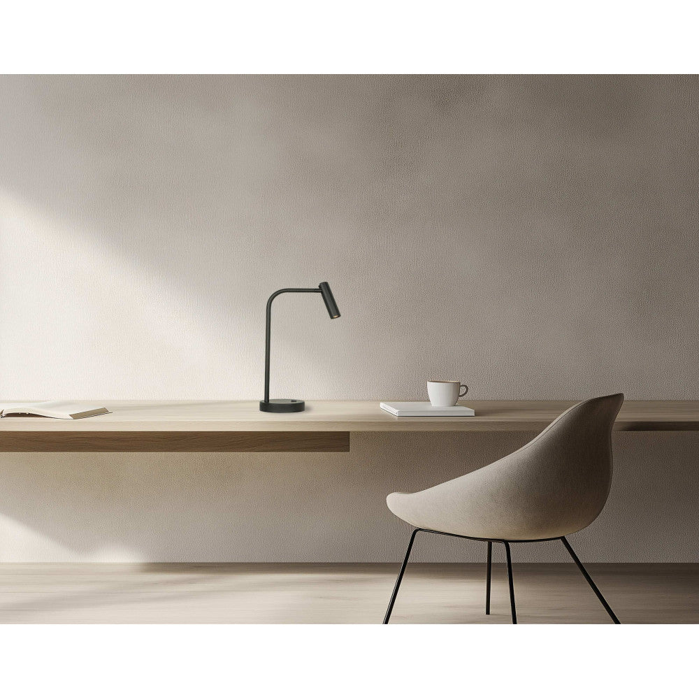 Vue de profil, lampe noire sur bureau en bois devant un mur texturé beige clair