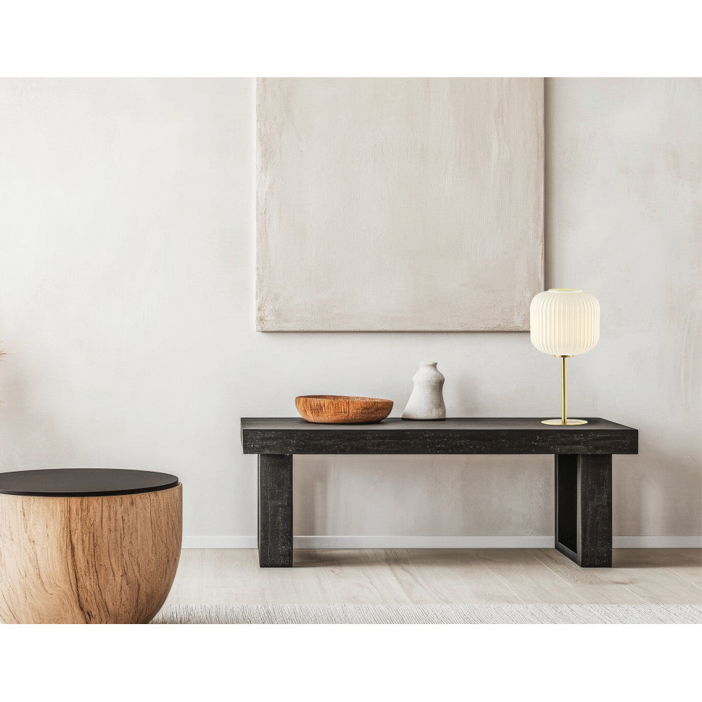 Lampe allumée sur une console noire, près d'une sculpture et d'un tableau beige