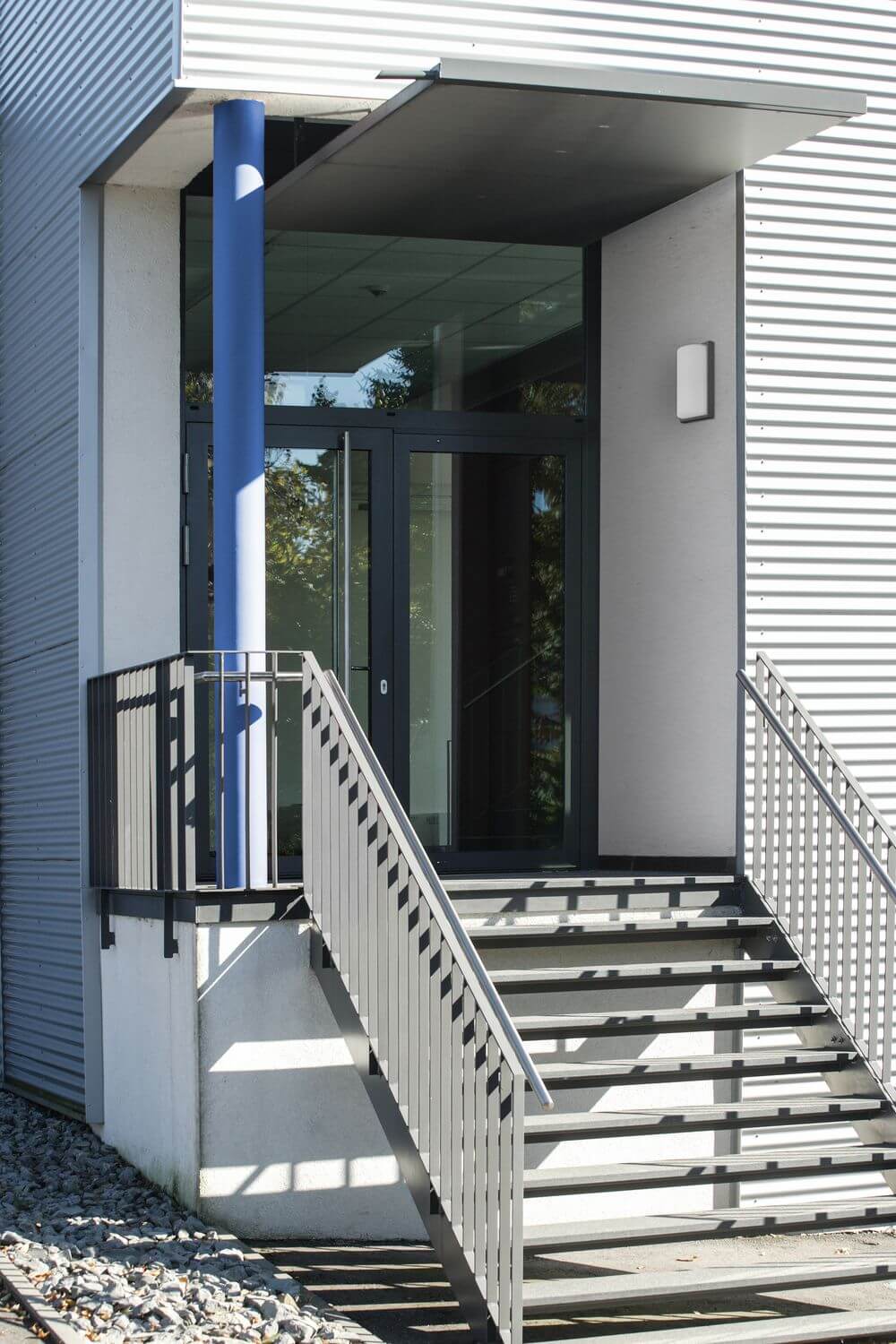 Mise en ambiance à l'entrée d'un bâtiment, applique fixée sur mur gris