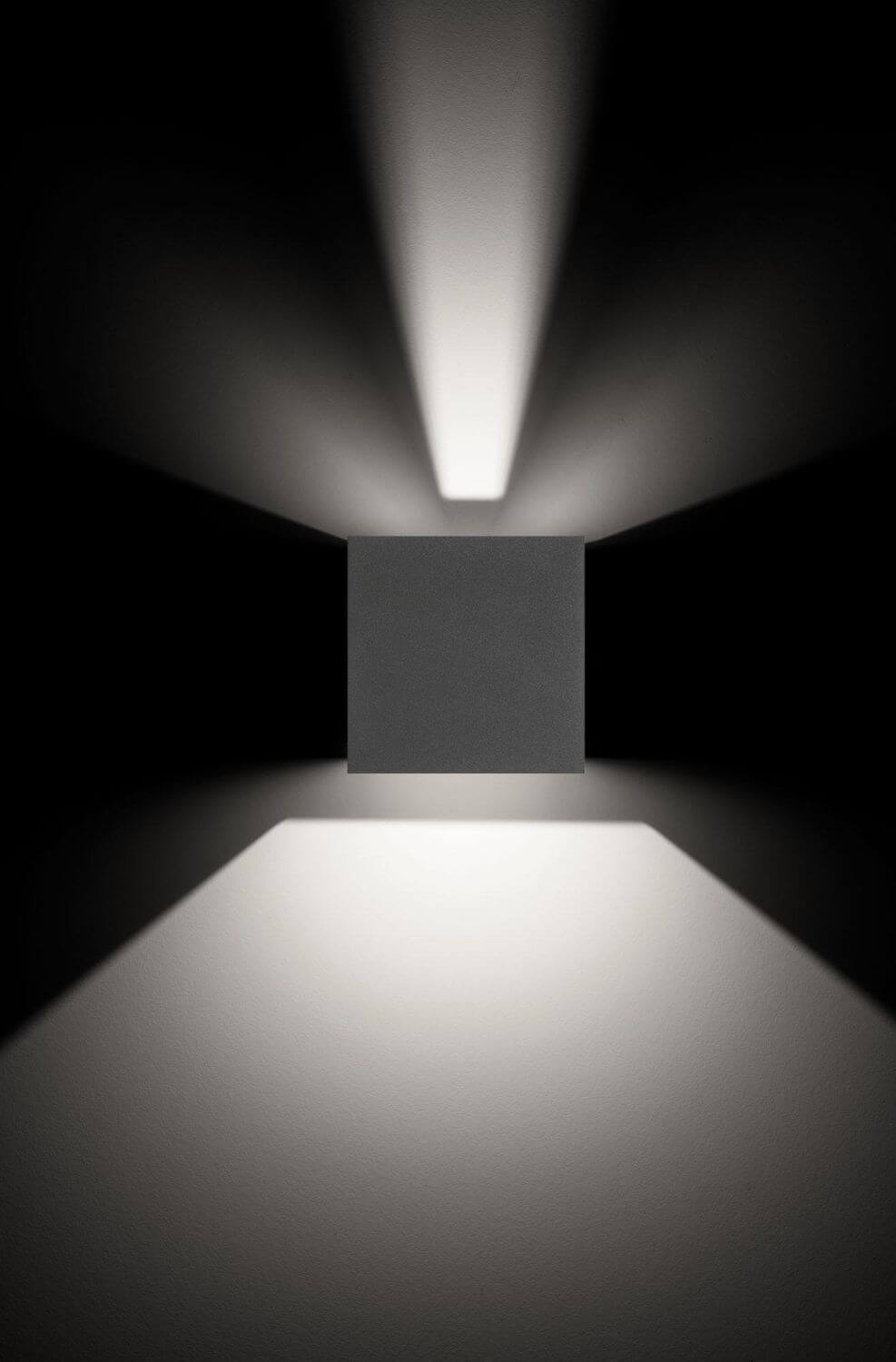 Vue rapprochée du boîtier carré anthracite et de ses faisceaux lumineux verticaux.