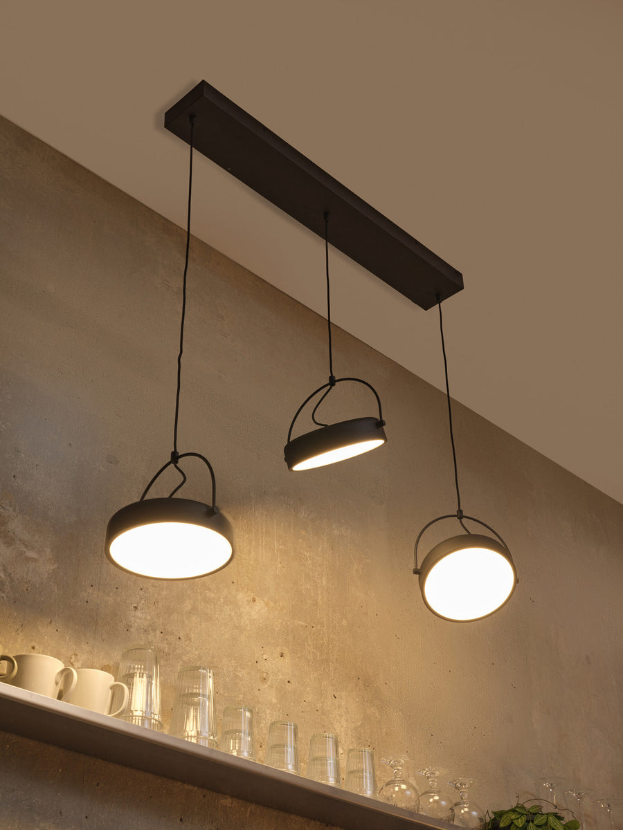 Vue en contre-plongée du luminaire allumé au-dessus d'une étagère garnie.