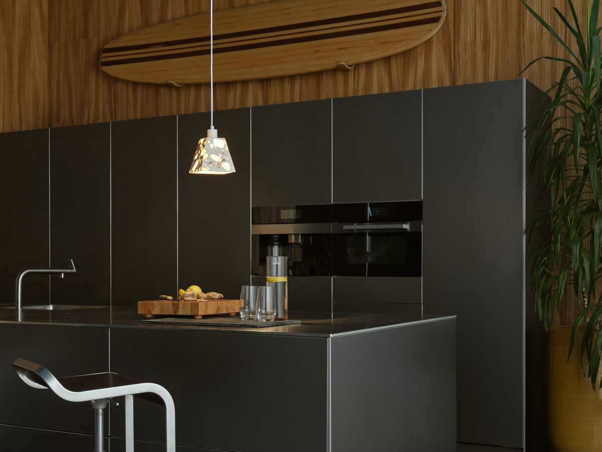 Suspension allumée au-dessus d'un îlot de cuisine noir, dans une ambiance moderne.