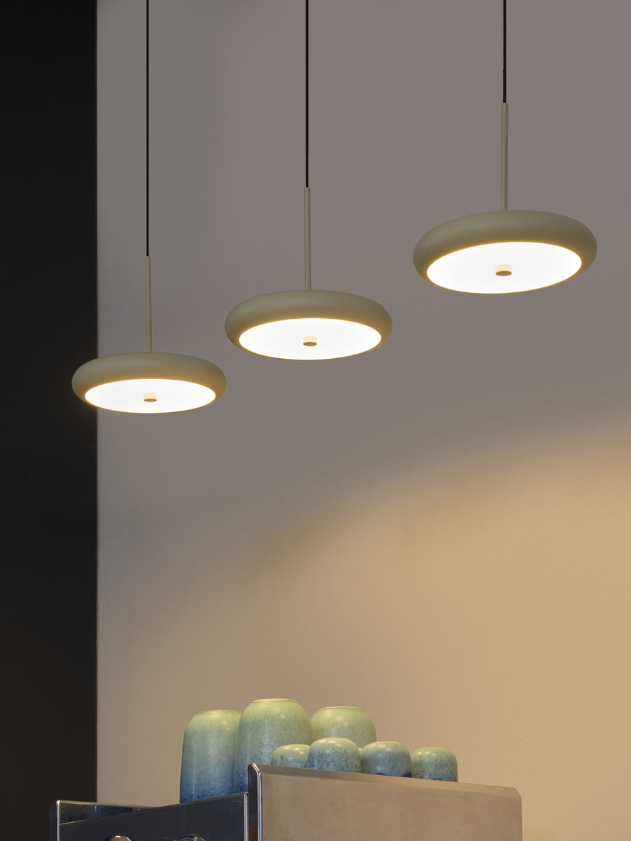 Détail de trois abat-jours ronds allumés, vus de près au-dessus de vases décoratifs.