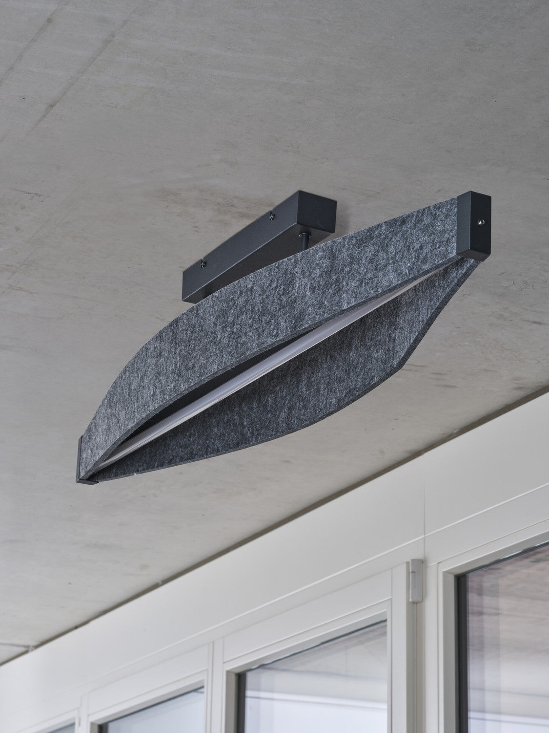 Détail de la finition, gros plan sur le plafonnier installé sur un plafond en béton brut.