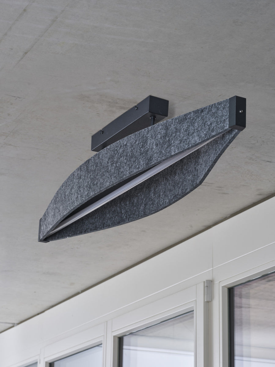 Détail de la finition, gros plan sur le plafonnier installé sur un plafond en béton brut.