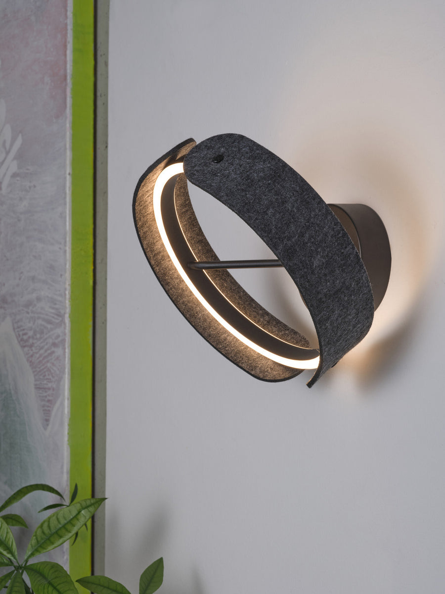 Vue latérale de l’applique allumée, halo lumineux et ruban de feutre anthracite.
